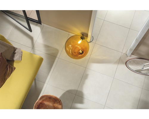 Overzicht van een kamer met vloertegels, lamp, bank en fiets