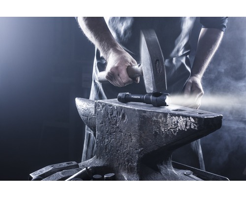 Een Varta zaklamp op een aambeeld, met een hamer erboven