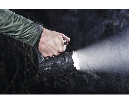 Een persoon houdt een Varta handlamp in de regen vast.