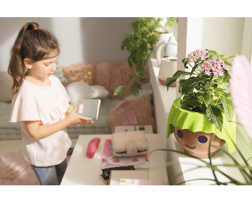 Meisje met notitieboek naast bloempot met gezicht ontwerp in kinderkamer.