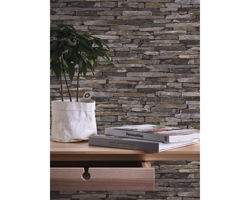 Wandbekleding met steenlook, plant in papieren zak en boeken op een houten bureau