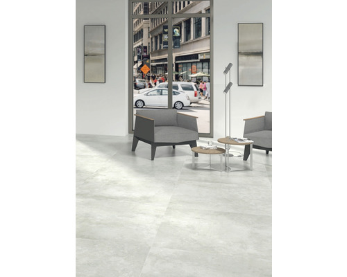 Lichte ruimte met vloertegels, fauteuil en uitzicht op een drukke stadsstraat.