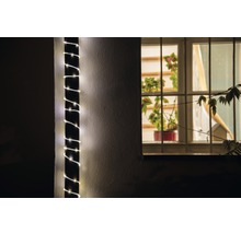 Buitenaanzicht van een huis met een lichtketting om een pilaar en een raam met planten.