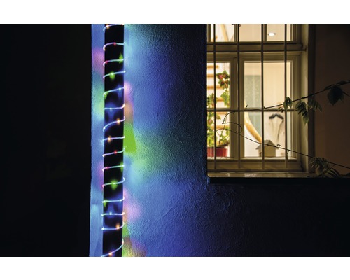 Buitenfoto van een huismuur met een LED-lichtsnoer ernaast, naast een raam.