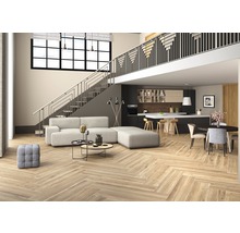 Lichte woonkamer met visgraat parketvloer, trap en open keuken.