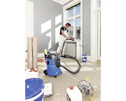 Een scène van een vakman die renovatiewerkzaamheden uitvoert met een nat- en droogzuiger.