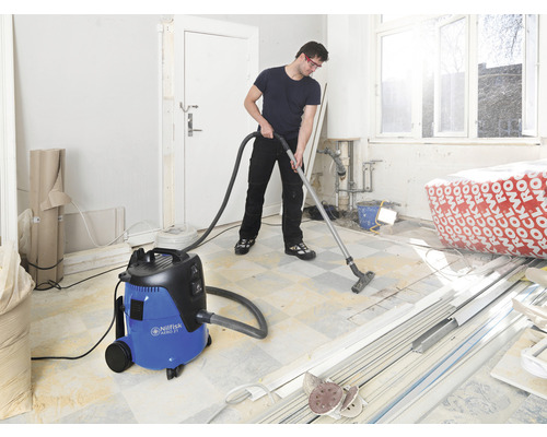 Man stofzuigt een kamer tijdens een renovatie met een Nilfisk alleszuiger.