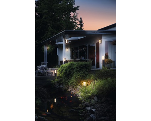 Buitenkant van een huis met tuinverlichting in de buurt van een vijver