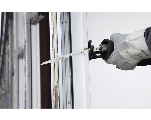 Een decoupeerzaag snijdt door een raamkozijn