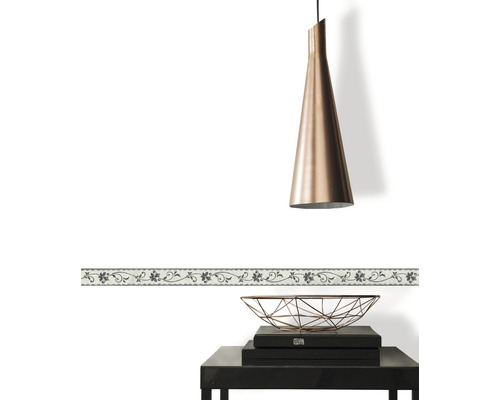 Decoratieve rand met bloemmotief op een witte muur, gecombineerd met een hanglamp en een bijzettafel.