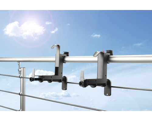 Twee balkonbakbevestigingen aan een reling tegen een blauwe lucht