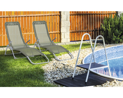 Twee metalen en stoffen ligstoelen naast een zwembad met een ladder.