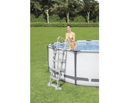 Opzetzwembad met ladder en vrouw in de tuin.