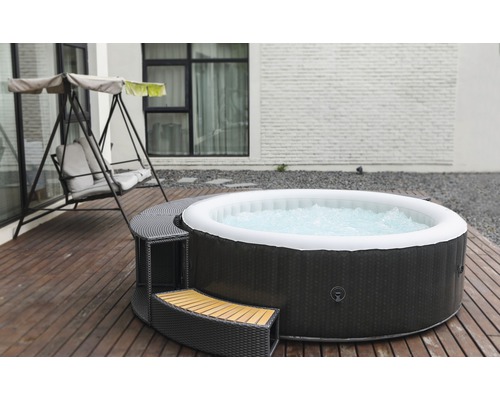 Opblaasbare whirlpool met ombouw en schommelstoel op een houten terras.
