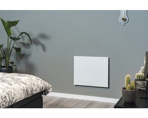 Woonkamer met gemonteerde, witte wandverwarming naast een bed en planten