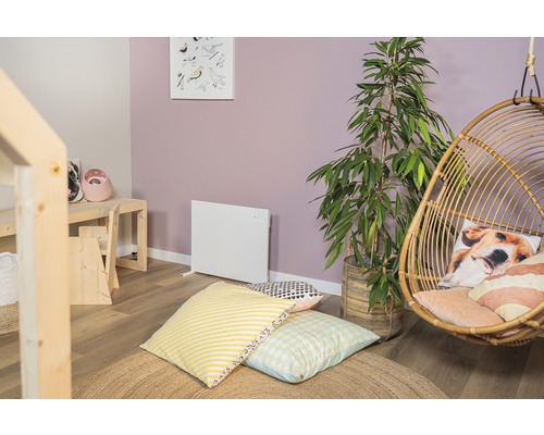 Woonkamer met radiator, hangstoel, kamerplant en kussens op een rond vloerkleed