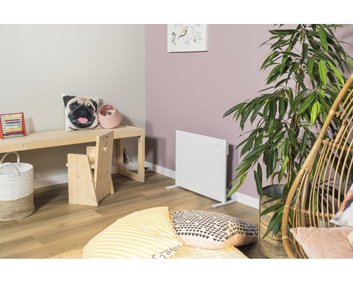 Licht ingerichte kinderkamer met radiator, houten tafel en zitje.