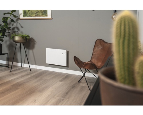 Woonkamer met elektrische verwarming aan de wand en lederen fauteuil