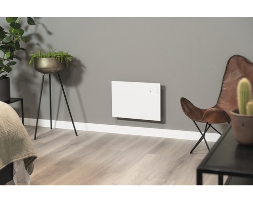 Woonkamer met wandverwarming, plantenbakken en lederen fauteuil.