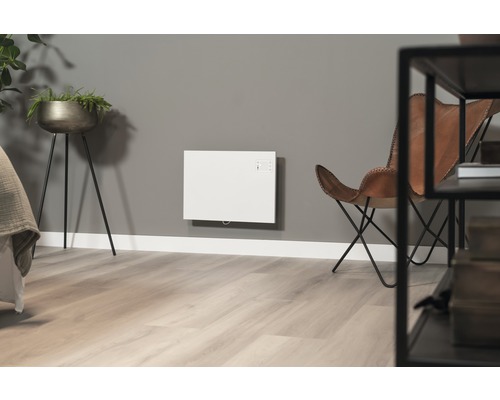 Woonkamer met wandverwarming, fauteuil en plant