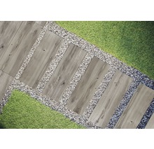 Tuinscene met houten loopplaten, omgeven door grind en gras