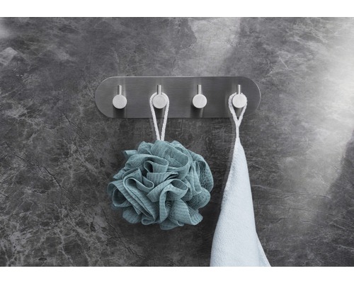 Wandkapstok met vier metalen haken, waaraan een badspons en een handdoek hangen.