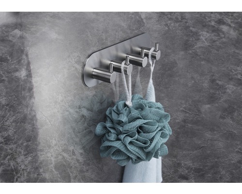 Handdoekhouder met vier metalen haken aan een muur met een badspons.