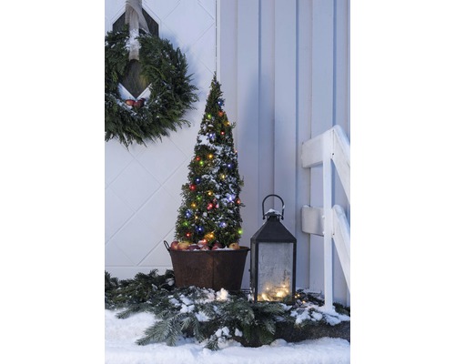 Winterse buitendecoratie met verlichte boom, krans en lantaarn.