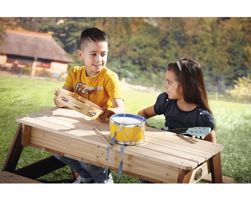 Twee kinderen spelen buiten aan een picknicktafel met muziekinstrumenten.