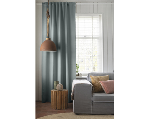 Woonkamer met gordijn, lamp, bijzettafel en bank.