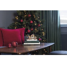 Kerstdecoratie met boom, ballen, lichtjes en decoratief winterlandschap op een tafel