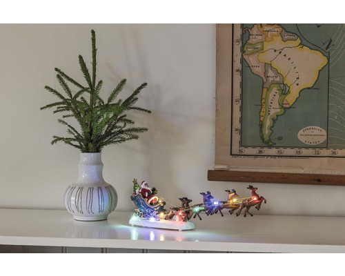 Decoratieve scène met dennenappeltakken in een vaas, een verlicht kerstmanslee figuur en een kaart van Zuid-Amerika.