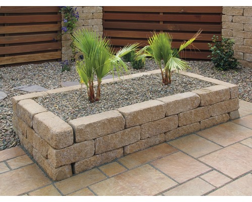 Verhoogde tuinbak van stenen blokken met planten en grind in de tuin