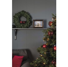 Feestelijk versierde woonkamer met kerstboom, krans en decoraties op een plank