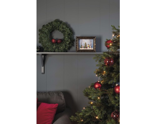 Feestelijk versierde woonkamer met kerstboom, krans en decoraties op een plank