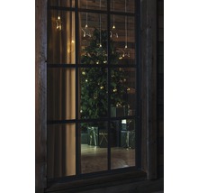 Uitzicht door een raam op een kerstboom met cadeaus en sterrenlichtjes