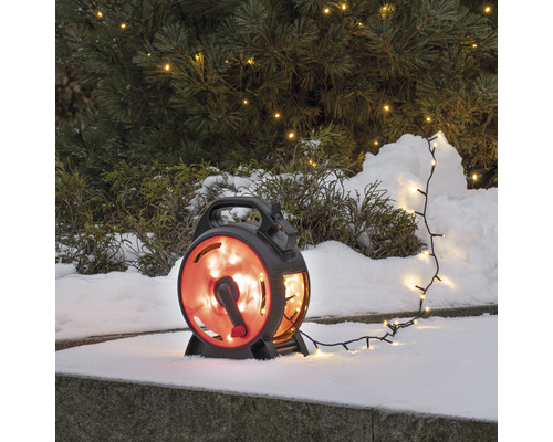 Lichtsnoer met haspel in de sneeuw voor een boom