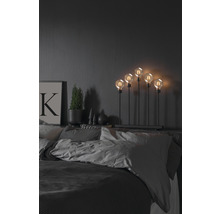 Decoratieve lamp met vijf gloeilampen op een nachtkastje in de slaapkamer.