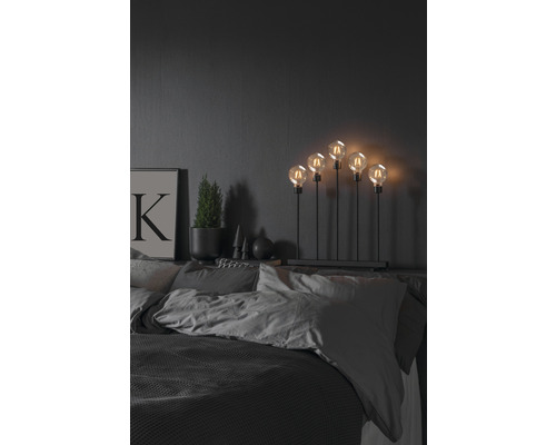 Decoratieve lamp met vijf gloeilampen op een nachtkastje in de slaapkamer.