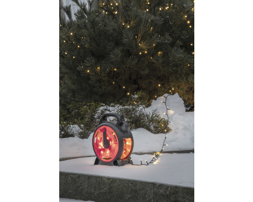 Slingers op haspel in de sneeuw voor een verlichte boom