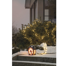 Winterse tuinscène met verlichte struik en decoratieve lantaarn op een trap