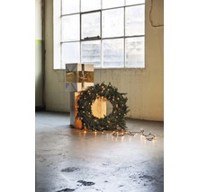 Decoratieve kerstscène met stapel cadeaus, sparrenkrans en lichtsnoer voor een raam