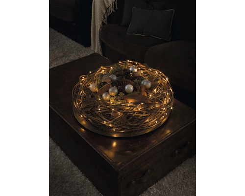 Decoratieve krans met LED-lichtslinger en kerstversiering op een tafel