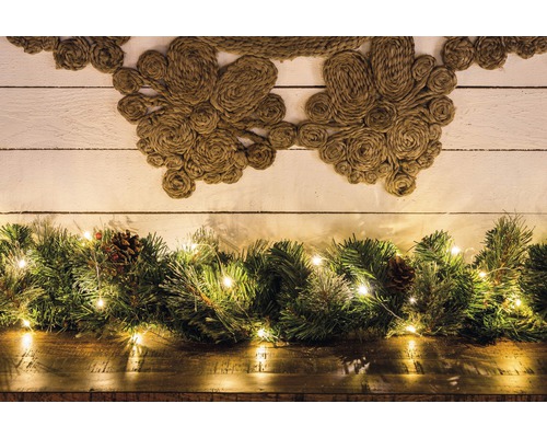 Decoratief arrangement met jute krans, groene takken, lichtsnoer en dennenappels
