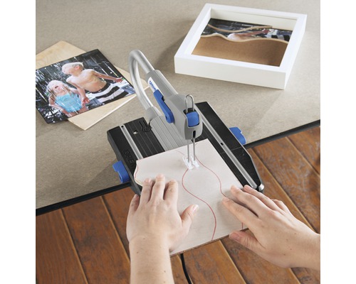 Dremel decoupeerzaag tijdens het bewerken van een stuk hout, omgeven door een foto en een fotolijst.