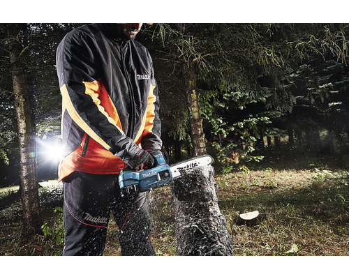 Een persoon gebruikt een Makita draadloze kettingzaag om een boomstam buiten te zagen.