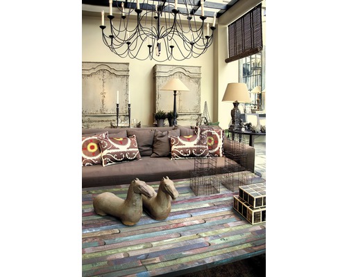 Woonkamer met bruine bank, houten salontafel, decoratieve objecten en kroonluchter.