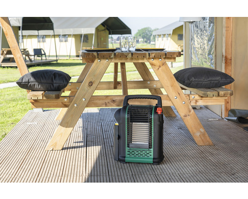 Kampeerscène met picknicktafel, kussens en draagbare kachel