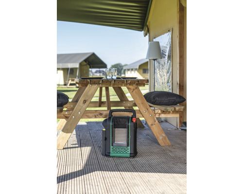 Campingplaats scène met picknicktafel, campingkachel en tenten op de achtergrond.