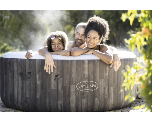 Familie ontspant in de Lay-Z-Spa Bahamas bubbelbad in de tuin.